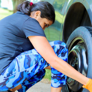 a woman kneels down to put on a spare tire