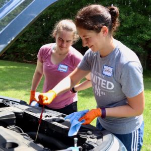 Two women check the oil level on a dipstick
